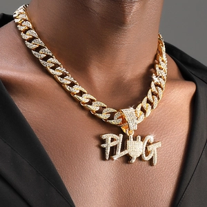 Detail van de gouden PLUG-hanger met fonkelende kristallen aan een grove Cubaanse schakel
