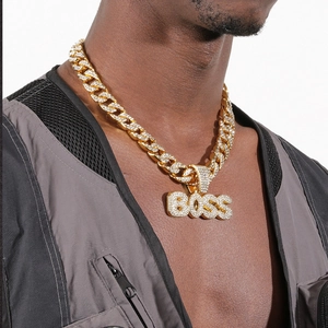 Gros plan du pendentif BOSS serti de strass avec une chaîne cubaine dorée sur modèle