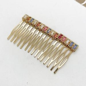 Detailed view of colorful rhinestones on a gold vintage hair comb and ten-tooth metal base