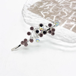 Detailopname van zilveren bloem haarspeld met paarse strass op glazen schaal