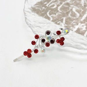 Detailopname van zilveren bloemen haarspeld met rode strass en gegraveerde wijnranken