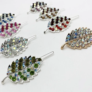 Macro detail of leaf-shaped hair clips with sparkling multicolor rhinestones and alloy base