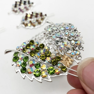 Leaf shaped hair clip with sparkling green and white rhinestones on silver metal base