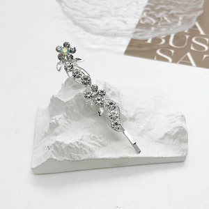 Détail d'une barrette argentée avec motifs de fleurs et papillons en strass sur socle