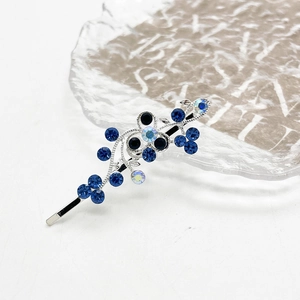 Detail van zilveren haarspeld met blauwe strassteentjes in bloemenrankontwerp op glas