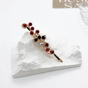 Vue détaillée de la barrette dorée en forme de branche avec strass rouges étincelants