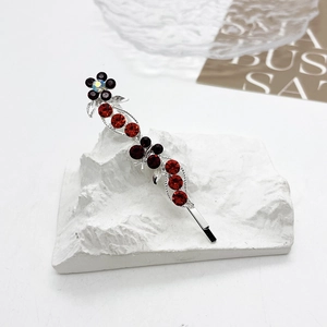 Détail d'une pince à cheveux florale en argent avec cristaux rouges et violets