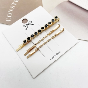 Detailweergave van de driedelige set met zwarte strass en gouden golvende haarspelden