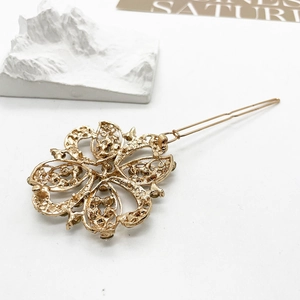 Detailed macro view of golden alloy flower medal hair clip with hollow pattern and pin
