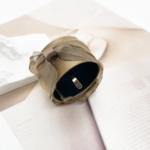 Detail of champagne gold mesh ponytail cuff featuring a metal hook and textured fabric