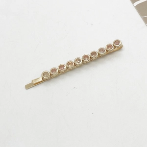 Detailed close-up of golden hair clip with row of eleven champagne rhinestones