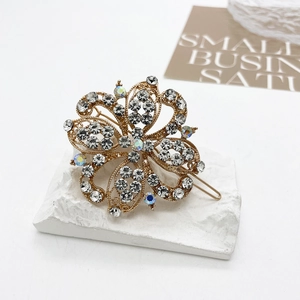Detailed macro of crystal-encrusted gold flower hair clip on a textured stone surface