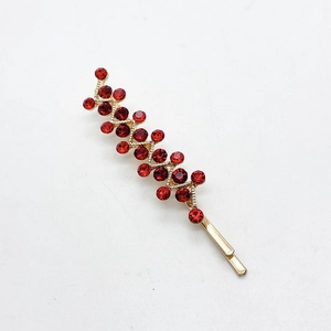 Detailed macro view of vibrant red rhinestones on a gold-tone wavy hair clip