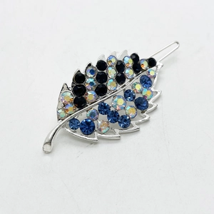 Macro shot of leaf-shaped hair clip with inlaid blue and black rhinestones and silver metal