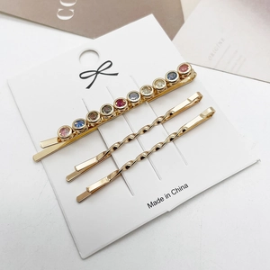 Detailset van drie gouden legering haarspelden met kleurrijke strass-steentjes