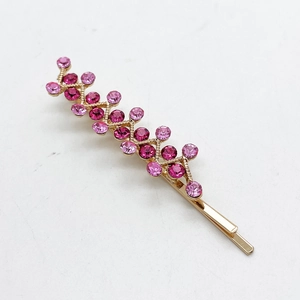 Macro detail of sparkling pink rhinestones on a gold metal hairpin for styling