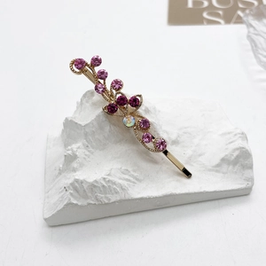 Vue macro de strass violets sur une barrette à cheveux florale dorée sur décor blanc