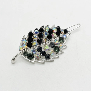Macro detail of leaf-shaped hair clip featuring colorful rhinestones on silver metal base