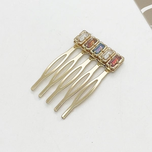 Detail of five-tooth gold alloy hair comb with five rectangular multicolored crystals