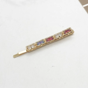Detail of gold-tone hair clip with five colorful rectangular rhinestones in a gradient