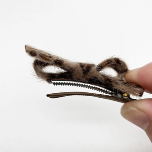 Dettaglio del fermaglio per capelli con fiocco leopardato in peluche e base metallica