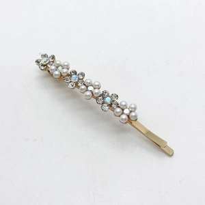 Detalle de un elegante pasador dorado con perlas y diamantes de diseño floral