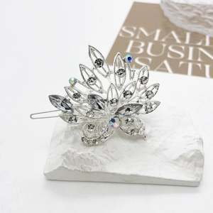 Detailed close-up of a silver rhinestone hair clip with floral crystal patterns on marble