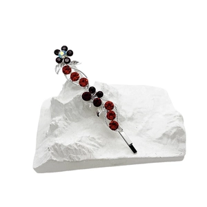 Barrette à cheveux argentée avec strass floraux rouges et noirs sur un support en pierre