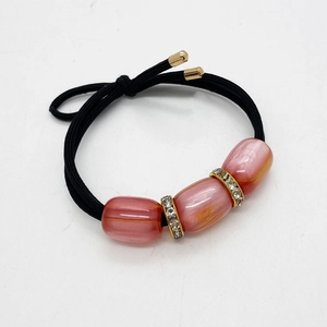 Dettaglio di elastico per capelli con perle in resina rosa e anelli di strass lucidi