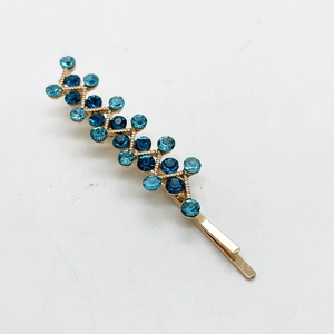 Detail of gold-tone hair clip with gradient blue rhinestones in a wave pattern