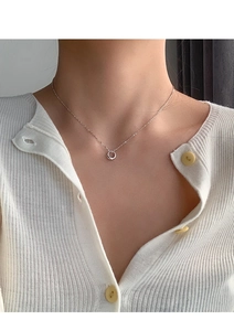 Close-up of minimalist silver plated donut ring necklace worn with a white knit cardigan
