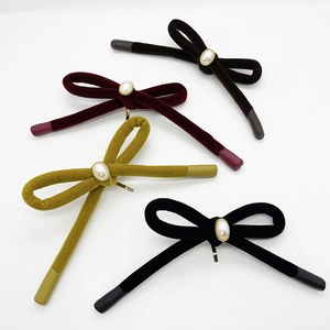 Detail view of four velvet bow hair clips with faux pearl embellishments in various colors