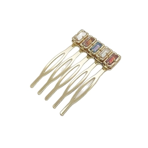 Golden five-tooth metal hair comb inlaid with rectangular colorful rhinestones on white background