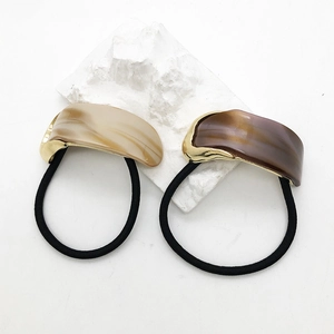 Elegant acetate marble hair ties with curved resin and gold metal link on white stone