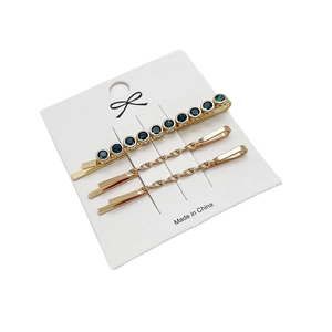 Driedelige gouden haarspeldjesset met blauwe strassteentjes op een witte display