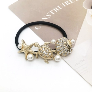Detailed macro view of golden starfish and shell charms with pearls on elastic hair tie