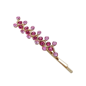 Golden rhinestone bobby pin with pink crystals in a geometric wavy pattern on white background
