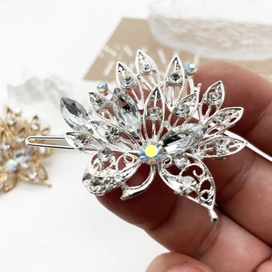 Close-up of a silver-tone floral hair clip with clear rhinestones and a central iridescent gem