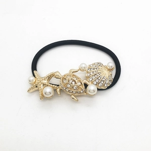 Macro detail of rhinestone sea star, turtle and shell charms on a black elastic hair tie