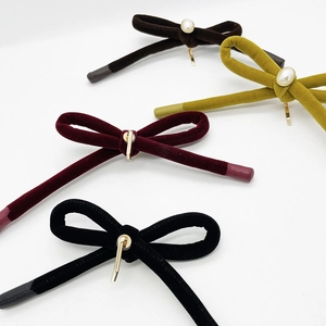 Close-up of velvet bow hair clips with pearls and metal clips in various colors