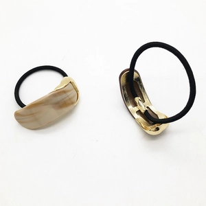 Detail view of marble resin hair tie with gold irregular metal base and black elastic band