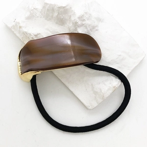 Detailed view of acetic acid hair tie with amber texture and golden metal base