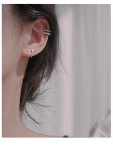 Detailed macro view of silver zircon ear cuffs and studs on female earlobe