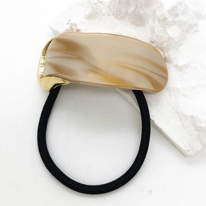 Detailed close-up of acetate hair tie featuring marbled resin and gold metal edges