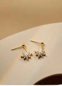Gros plan de boucles d'oreilles flocon de neige dorées avec zircons étincelants
