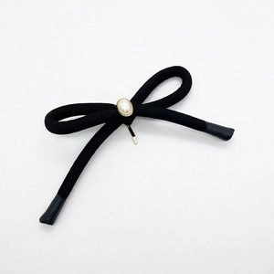 Detailed macro view of a black fabric bow hair clip with an elegant faux pearl center