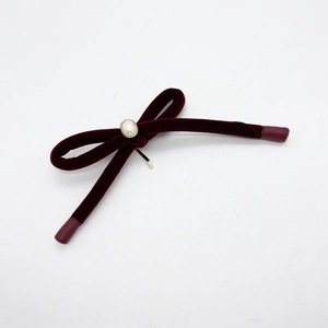 Detail view of burgundy velvet bow hair clip featuring a gold-edged faux pearl accent