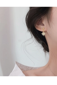 Vue détaillée de boucles d'oreilles flocon dorées avec zircon brillant sur un mannequin