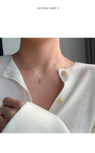 Detail of silver geometric circle pendant on minimalist chain worn on model neckline