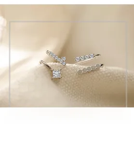 Macro shot of silver asymmetric ear cuffs with clear cubic zirconia on knit fabric